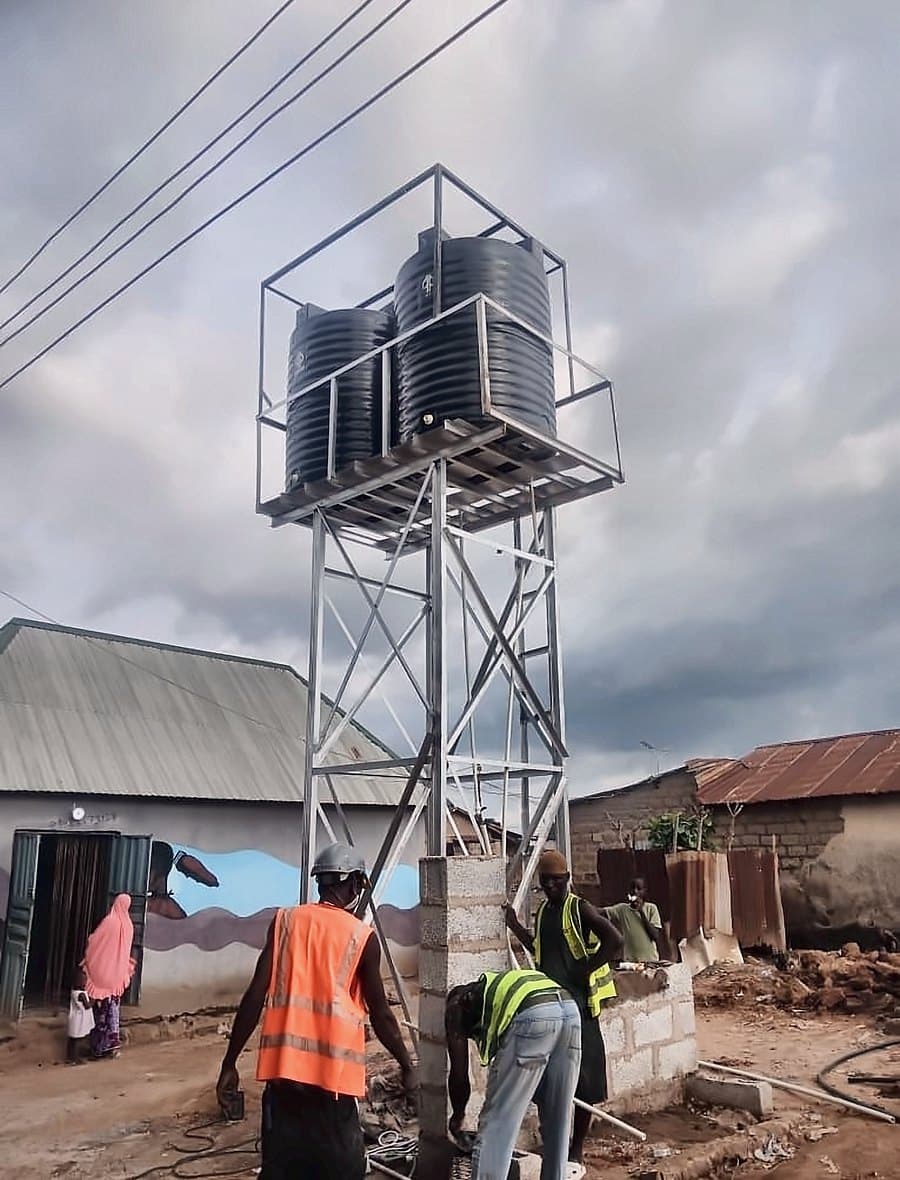 The build crew finishing the pump-house plinth beneath the water tower in Chukuku
